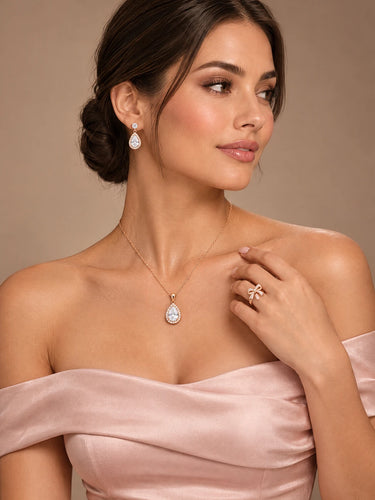 Model wearing rose gold pear halo necklace, earrings and bow ring